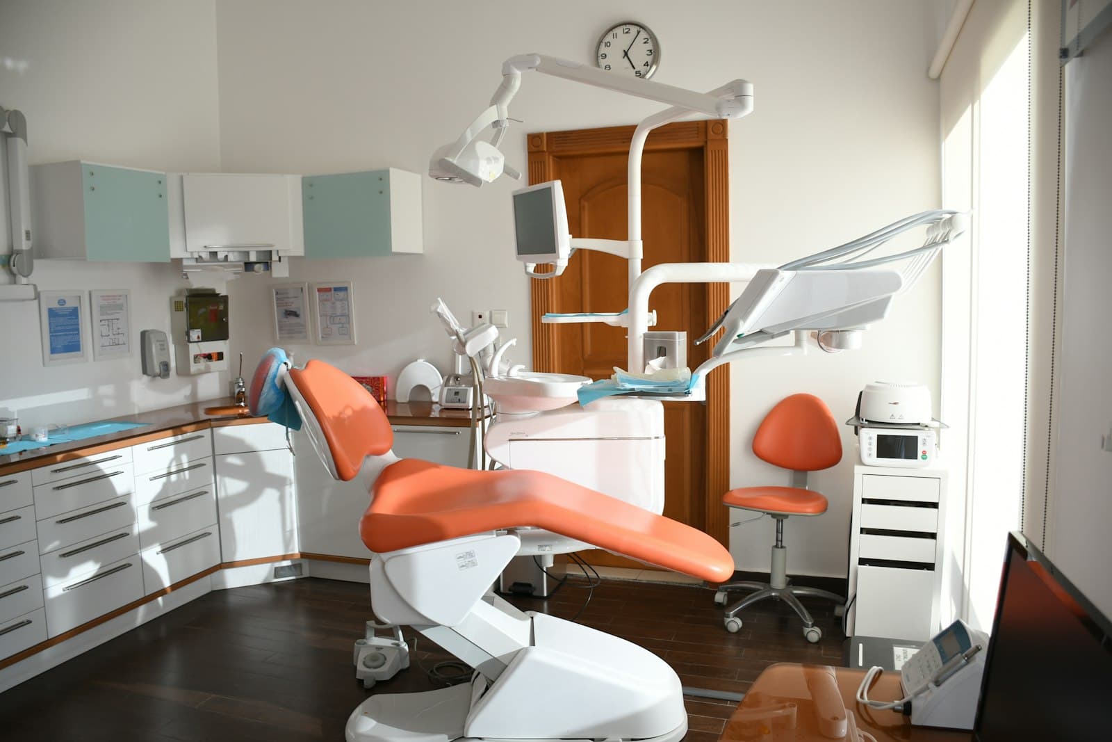 A bright dental treatment room with an orange chair