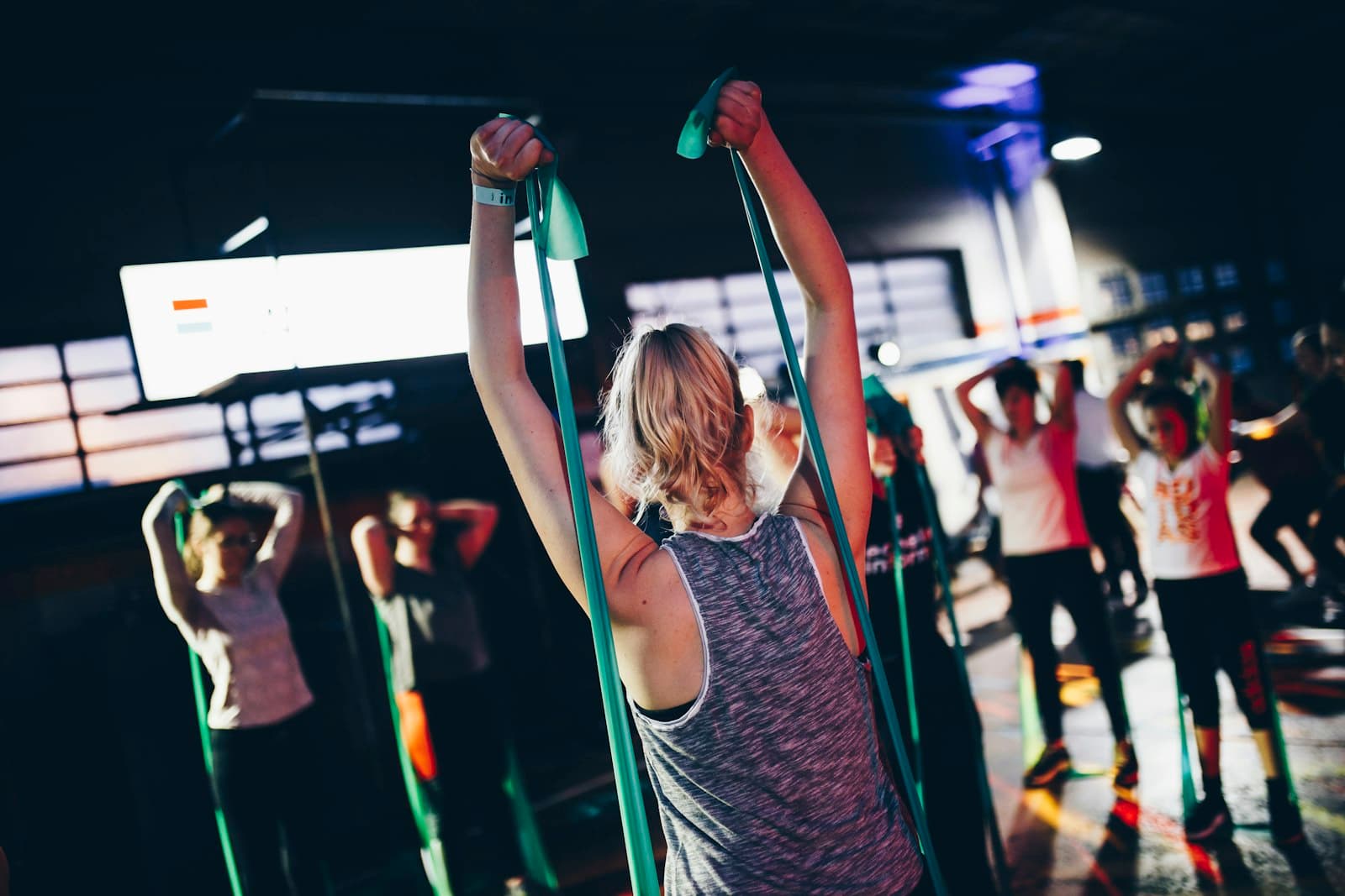 A group fitness class using resistance bands in a dim studio