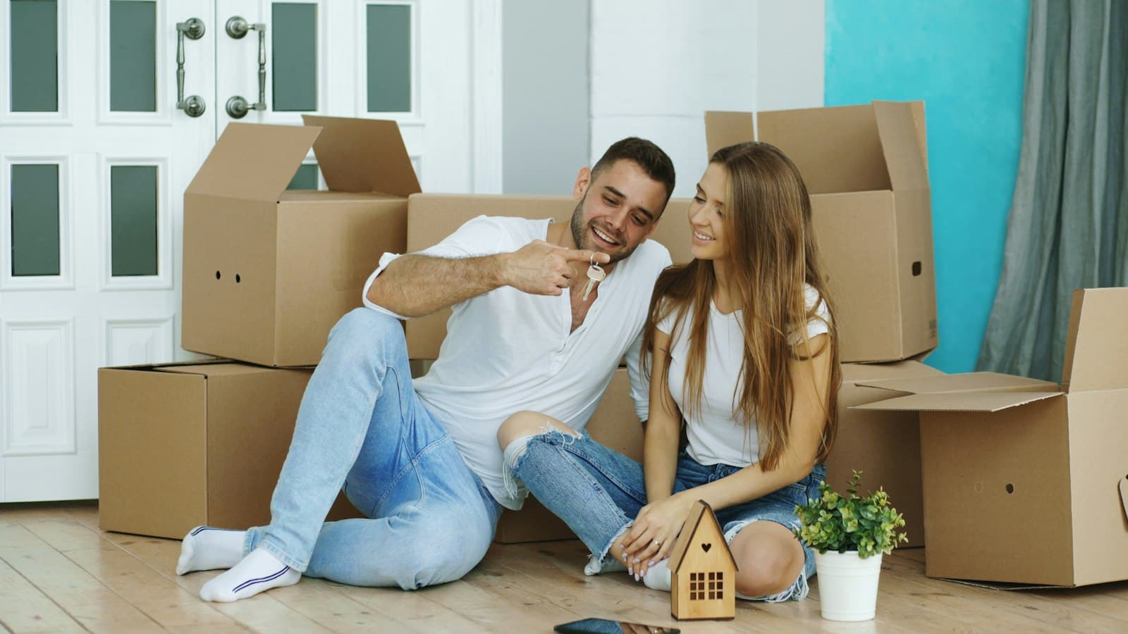 A couple sitting on the floor among moving boxes in their new home