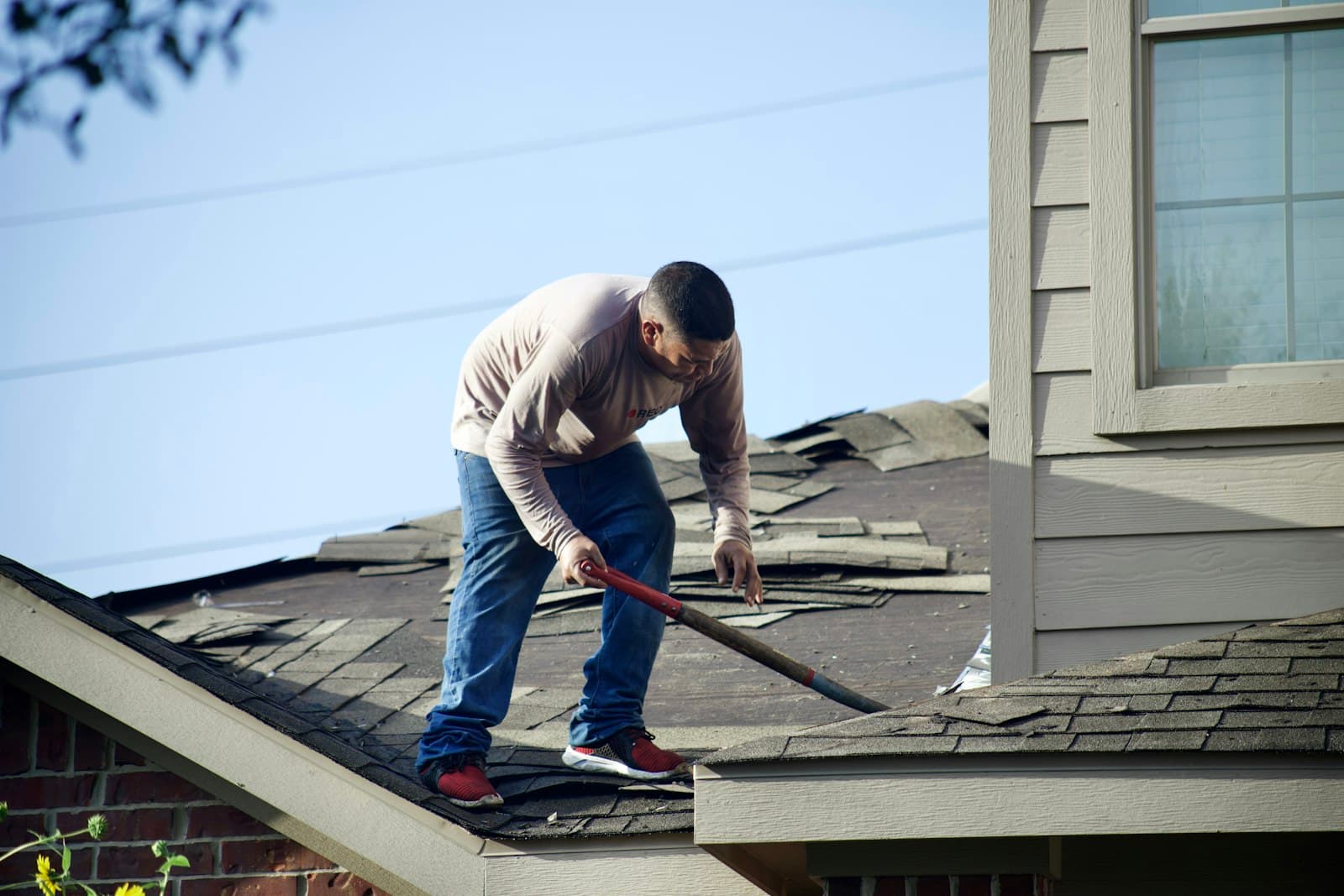 A roofer on a shingled roof, too busy to answer the phone